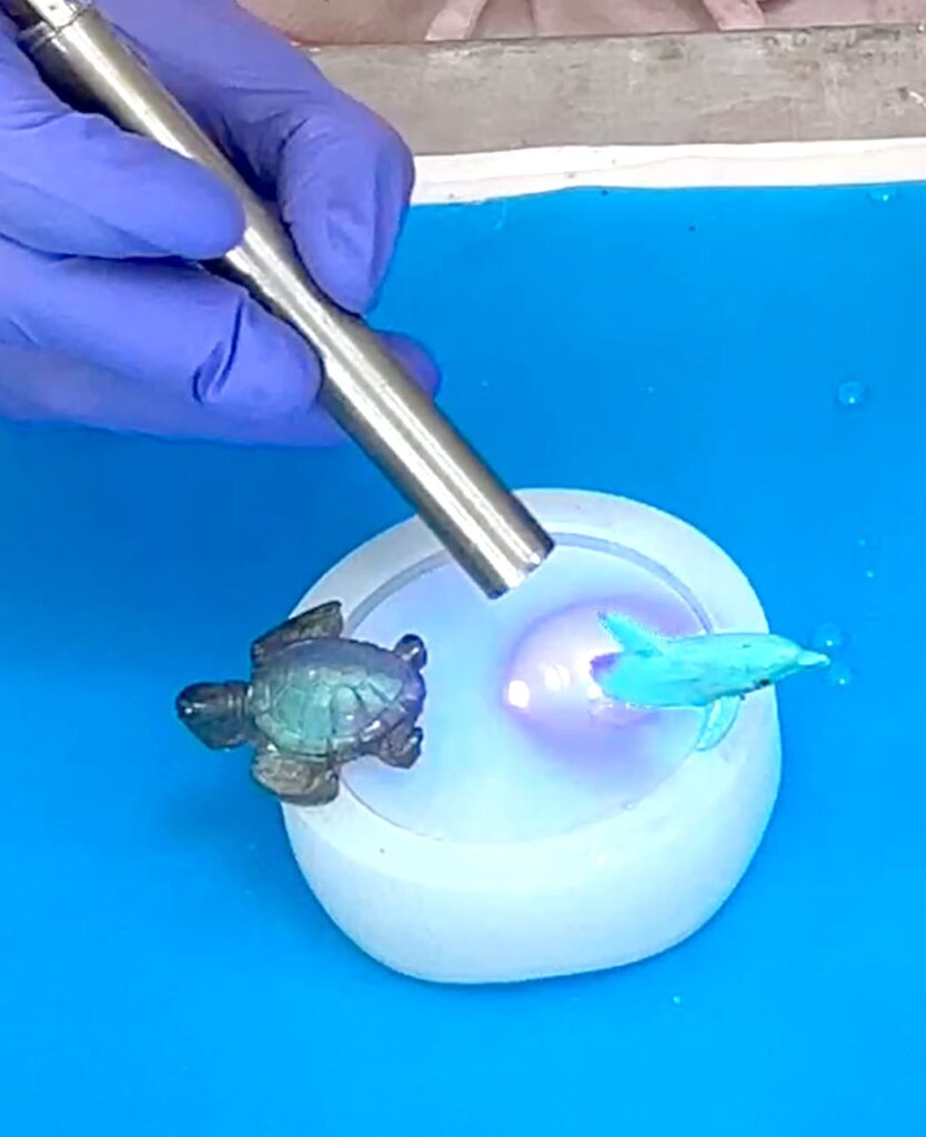 Using UV resin to attach dolphin and turtle on the best wine lover gift lid