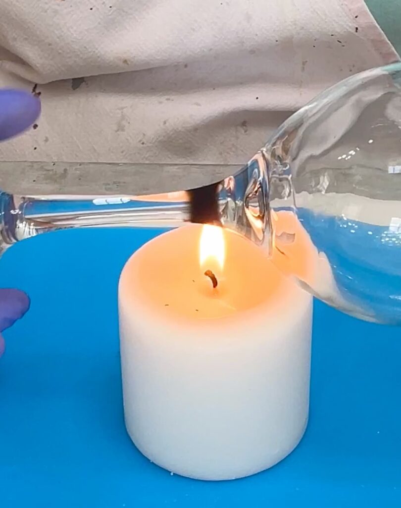 holding a glass stem over a candle flame