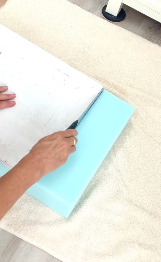 Using a knife to cut foam to show how to reupholster a bench