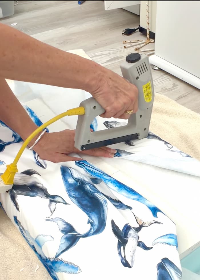 Using a stapler to attach fabric when reupholstering a bench
