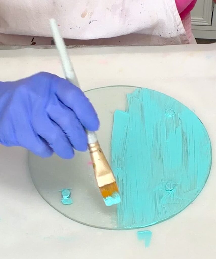 Painting a round glass cutting board with seafoam green paint