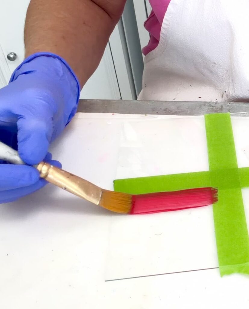 Painting red paint on glass with a paint brush