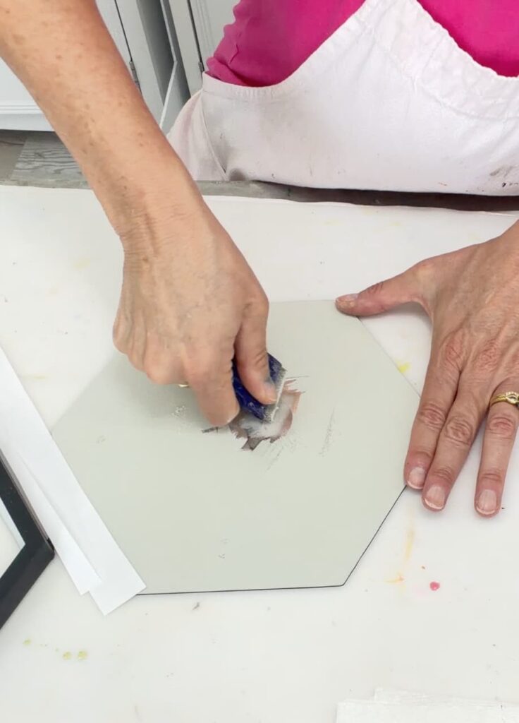 Scraping the back off the Dollar Tree mirror to prep it for the easy Halloween craft
