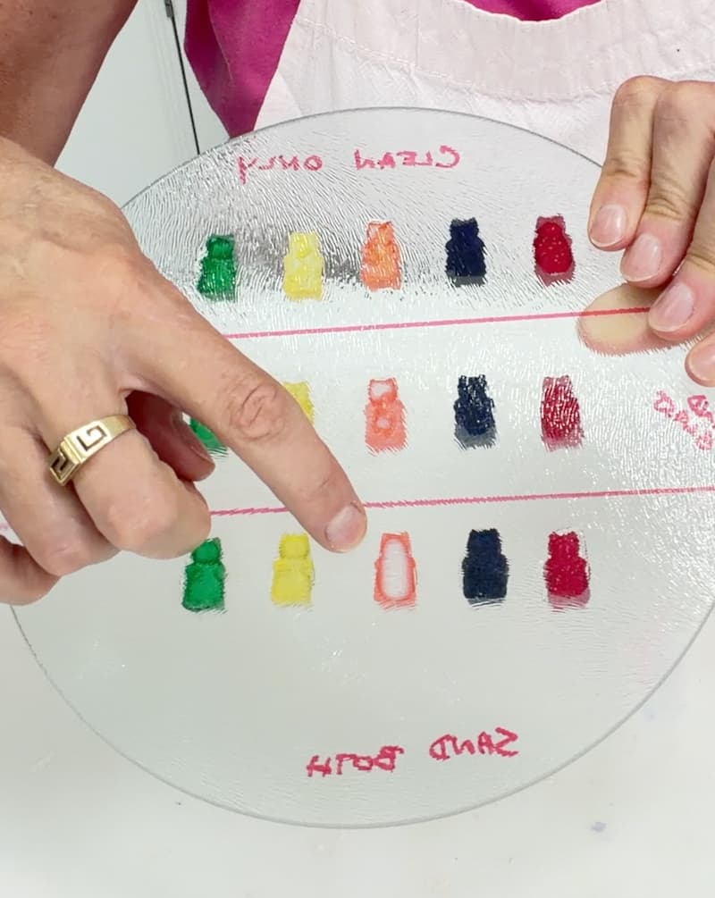 Pointing to the back of an orange gummy bear where the glue is still white and wet