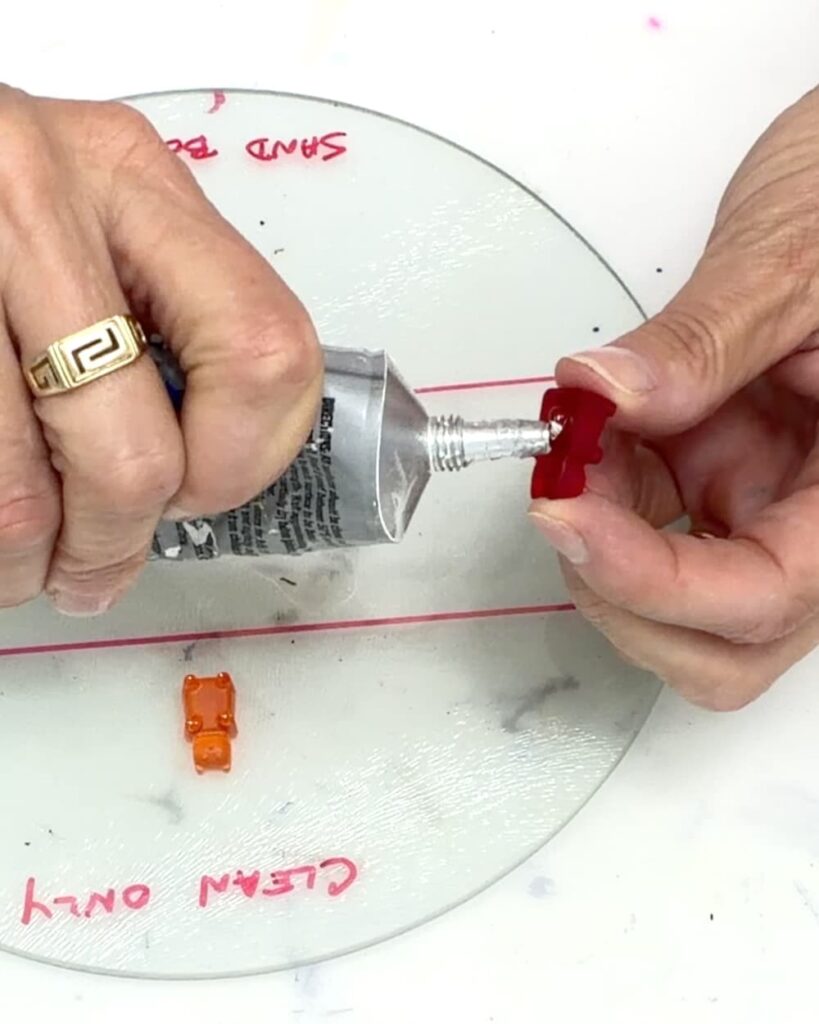 Testing the best glue for glass by squeezing clear glue onto the back of a red gummy bear