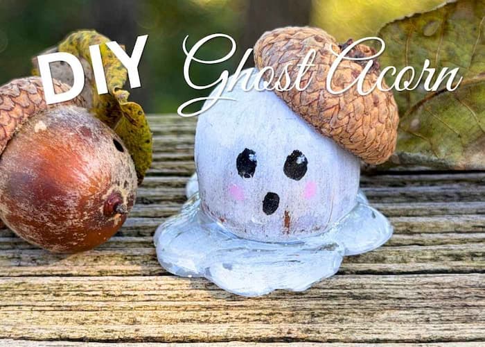 DIY Ghost decoration acorn craft sitting on wood with leaves and a natural acorn